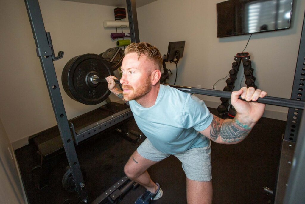 A person doing a back squat inside of a power lifting rack at the gym.